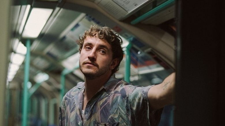 Paul Mescal with mustache standing on subway in All of Us Strangers