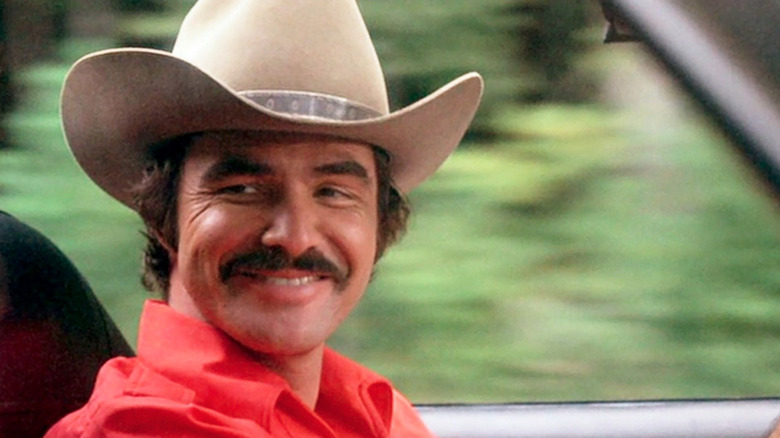 Burt Reynolds as Bo "The Bandit" Darville, smiling and driving in Smokey and the Bandit.