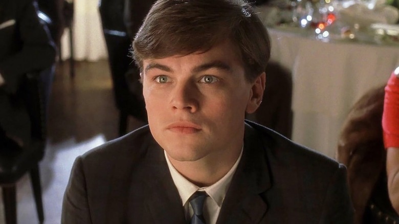 Leonardo DiCaprio as Frank Abagnale Jr., sitting at a table in Catch Me If You Can.