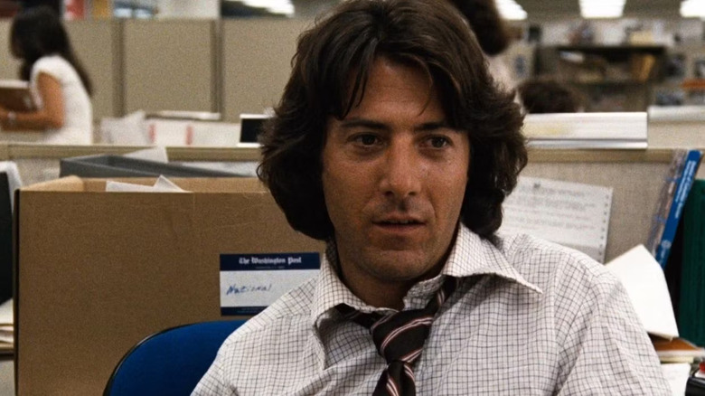 Carl Bernstein (Dustin Hoffman) sits at a desk in the newsroom in All the President's Men