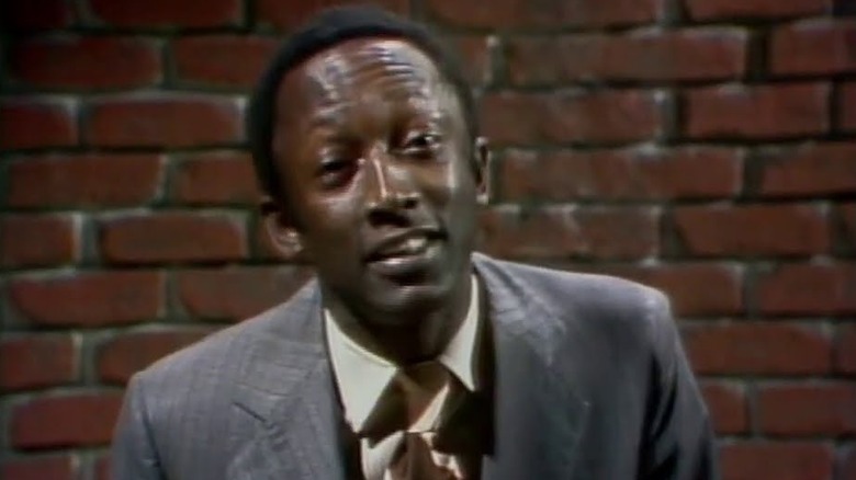 Garrett Morris speaking directly to camera against a brick wall on Saturday Night Live