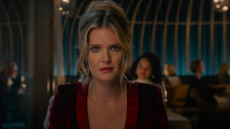 Meghann Fahy as Violet staring directly at camera in a red dress in Drop