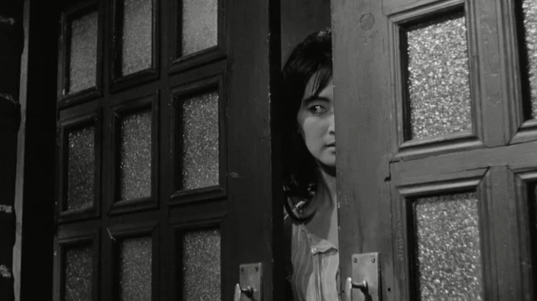 Myung-sook (Lee Eun-shim) peers through a sliding door in The Housemaid (1960)