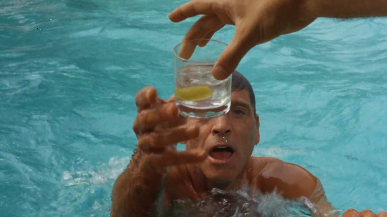 Ned Merrill (Burt Lancaster) reaches for a cocktail from a swimming pool in The Swimmer (1968)