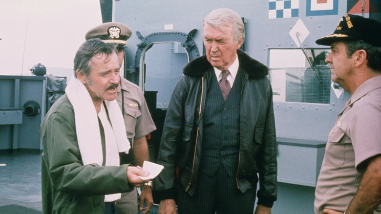 Don Gallagher (Jack Lemmon) speaks to naval officers on a ship's deck with Philip Stevens (James Stewart) in Airport '77