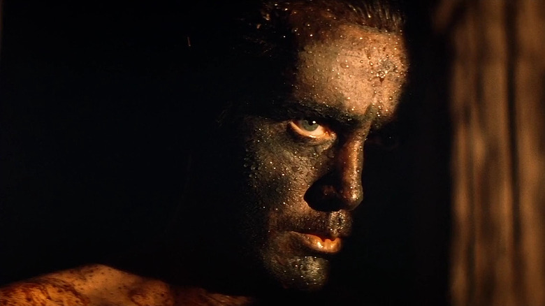 Martin Sheen as Captain Benjamin L. Willard in Apocalypse Now, his face half-lit out of the dark while he ears camouflage face paint.