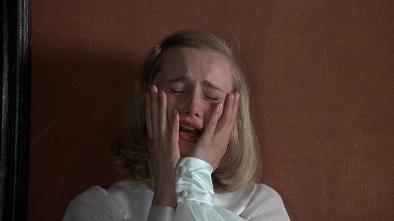 Renata Moar as Renata in Salò, or the 120 Days of Sodom, crying as she clutches her face.