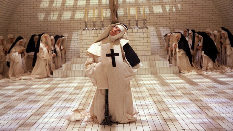 Vanessa Redgrave as Sister Jeanne des Anges kneeling in the center of a stark-white brick church interior, flanked by other nuns.