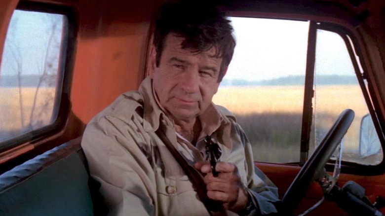Walter Matthau as Miles, pointing a gun in a truck in Hopscotch