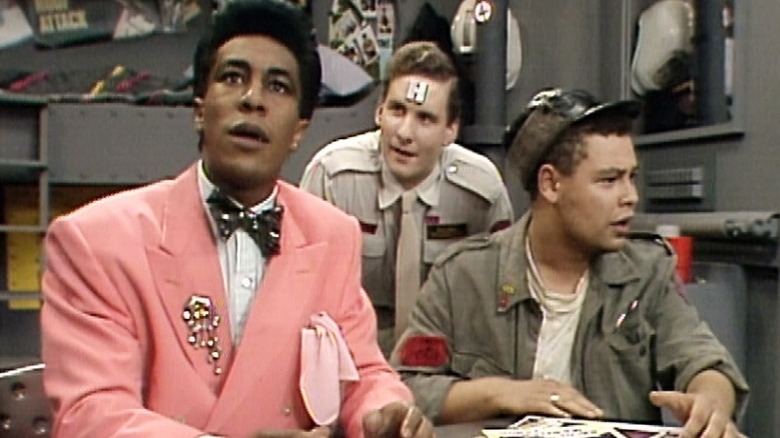 Cat (Danny John-Jules), Arnold Judas Rimmer (Chris Barrie), and Dave Lister (Craig Charles) gather around a table in Red Dwarf