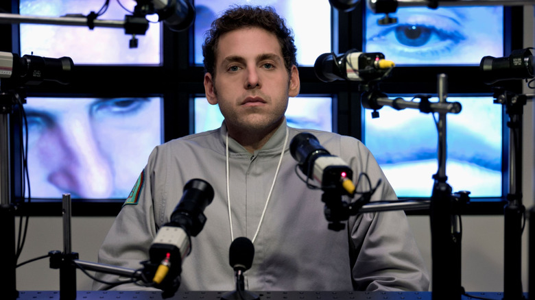 Jonah Hill as Owen Milgrim sitting with microphones in front of him in Maniac