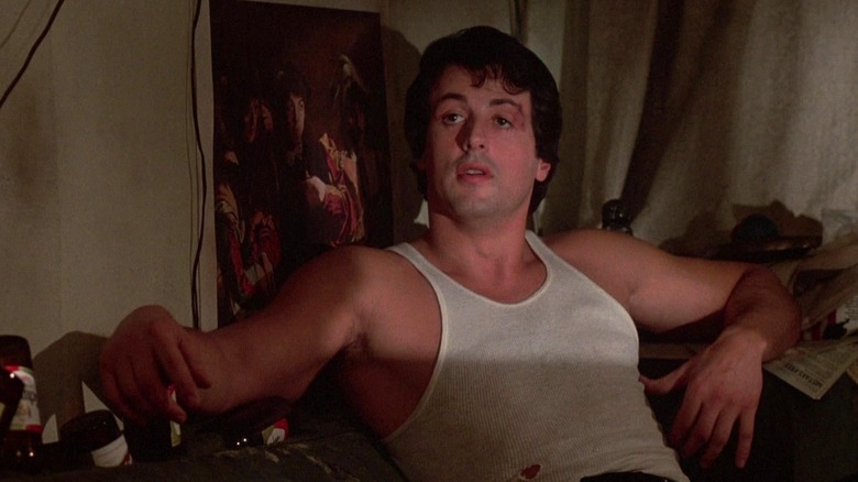 Sylvester Stallone as Rocky Balboa sitting on a couch in Rocky