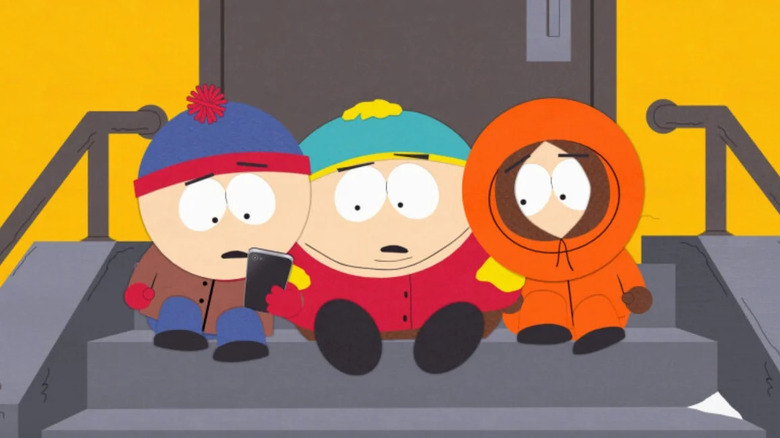 Stan, Cartman, and Kenny sit on the steps looking at an iPhone in South Park