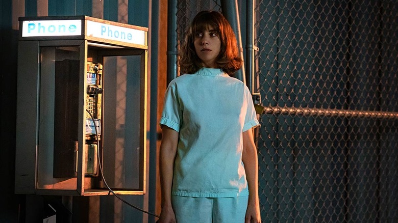 Alison Brie as Sarah, standing next to a payphone in Horse Girl