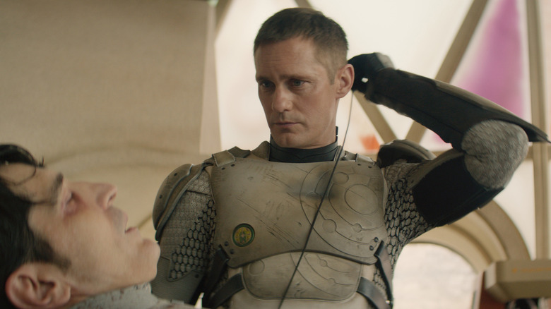 David Dastmalchian as Gurathin lying on a table while Alexander Skarsgård as Murderbot plugs into him on Murderbot