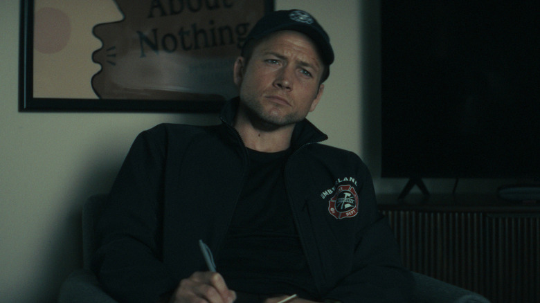 Taron Egerton's Dave Gudsen looking thoughtful and wearing a baseball cap on Smoke