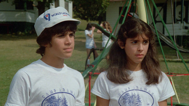 Ricky Thomas (Jonathan Tiersten) and Angela Baker (Felissa Rose) stand at a playground in Sleepaway Camp
