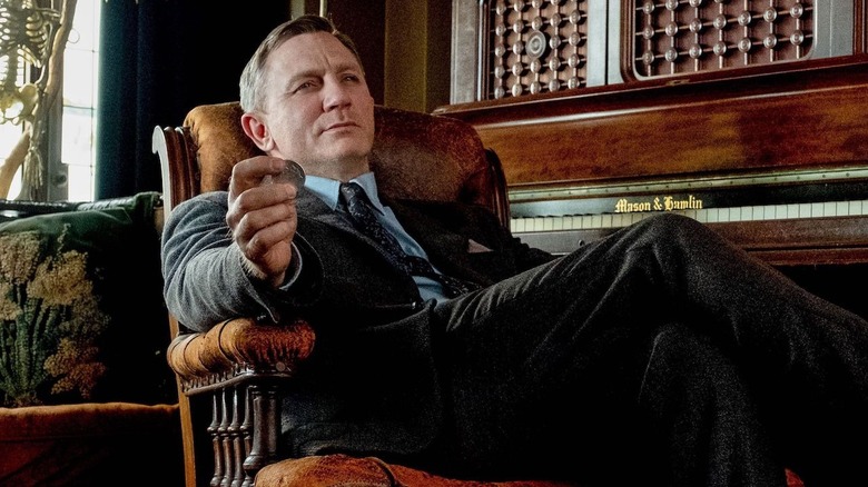 Daniel Craig as Benoit Blanc, leaning back in a chair in Knives Out