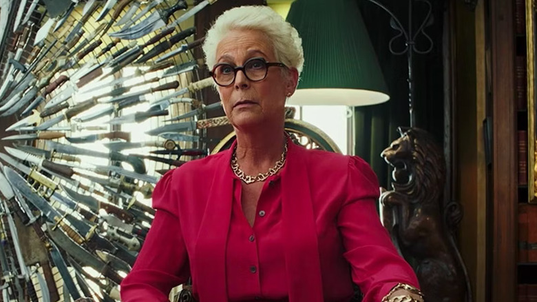 Jamie Lee Curtis as Linda Drysdale, sitting in front of the Thrombey knife sculpture in Knives Out