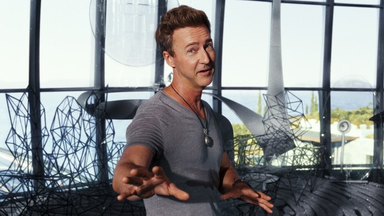 Edward Norton as Miles Bron, smiling in his glass enclosure in Glass Onion