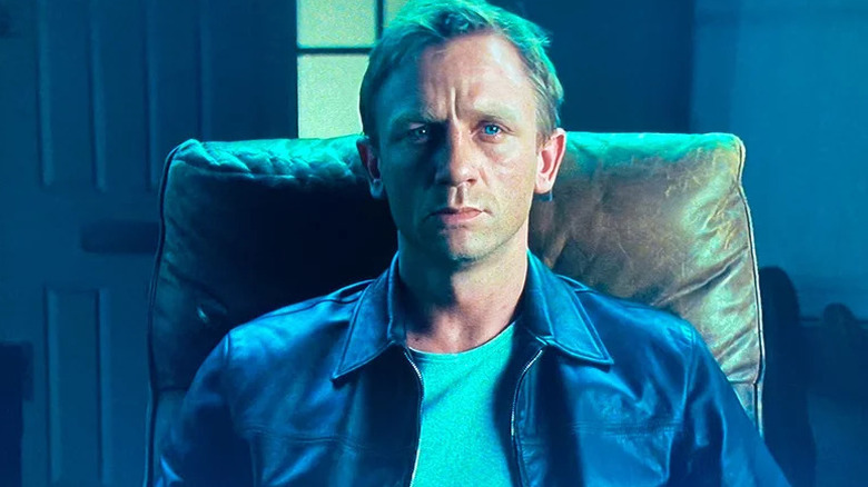 XXXX (Daniel Craig) sits in a leather chair in a blue-lit room in Layer Cake