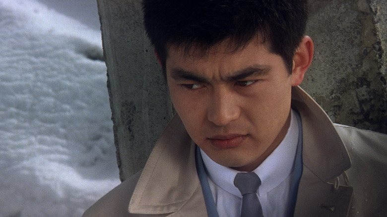 Phoenix Tetsu (Tetsuya Watari) leans against a stone column in the snow in Tokyo Drifter