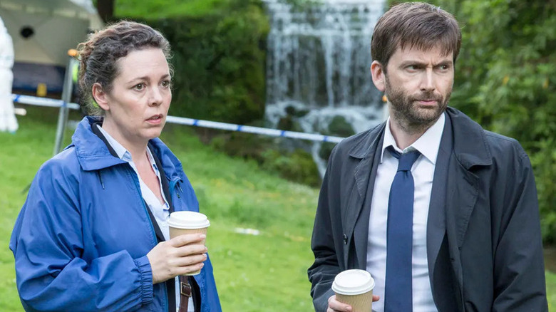 Olivia Colman as Ellie Miller in rain jacket with coffee cup next to David Tennant as Alec Hardy in suit and rain jacket with coffee in Broadchurch