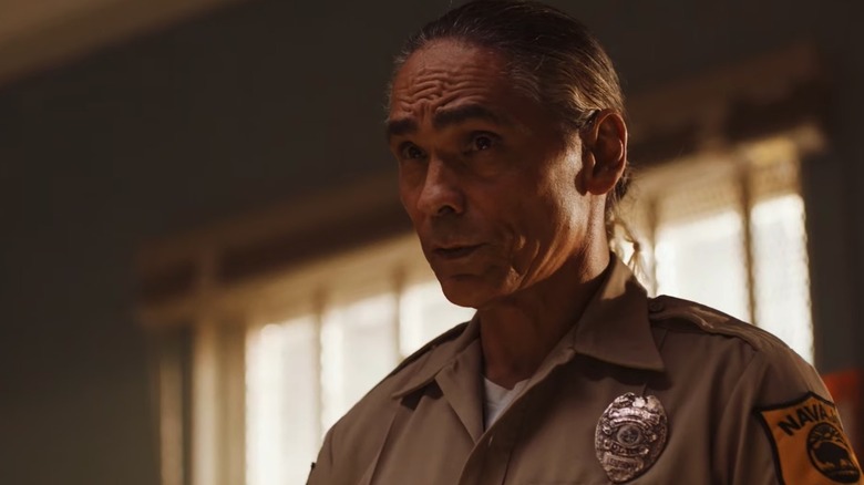 Zahn McClarnon as Joe Leaphorn with tan police uniform and hair in bun in Dark Winds