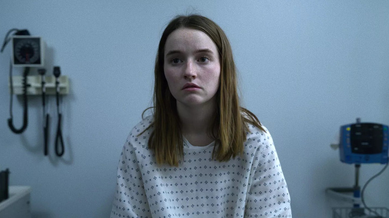 Kaitlyn Dever as Marie sitting in doctor's office in white hospital gown in Unbelievable