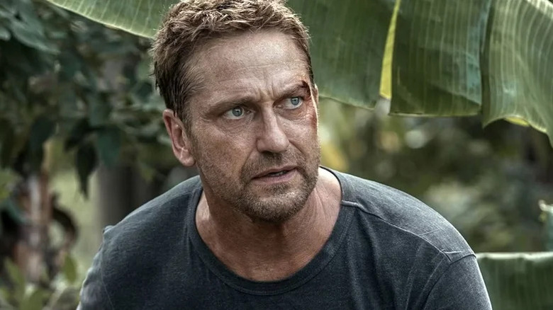 Gerard Butler in grey shirt with cut on his eyebrow in the jungle in Plane