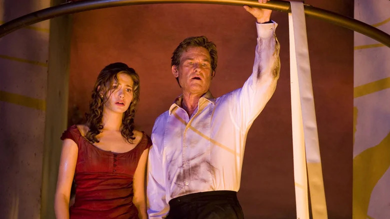 Emmy Rossum and Kurt Russell as Jennifer and Robert in dirty dress clothes looking down at something in Poseidon