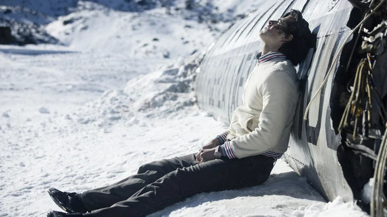 Enzo Vogrincic as Numa Turcatti with blood on face sitting in the snow leaning against crashed plane in Society of Snow