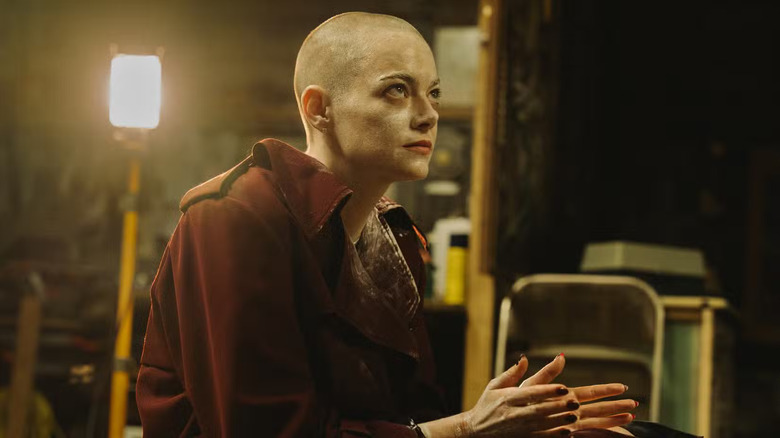 Emma Stone in a dirty coat with her head shaved as Michelle in Bugonia