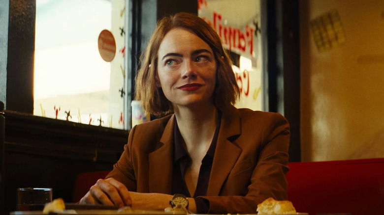 Emma Stone sitting in a restaurant booth as Emily in Kinds of Kindness