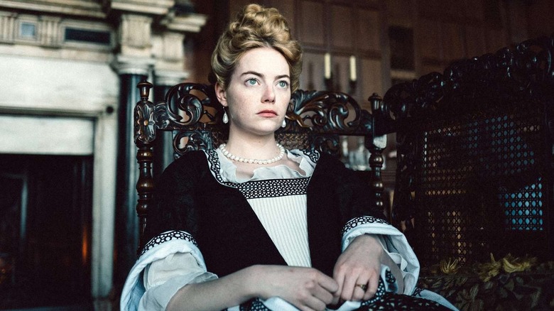 Emma Stone sitting in an ornate chair as Abigail Hill in The Favourite