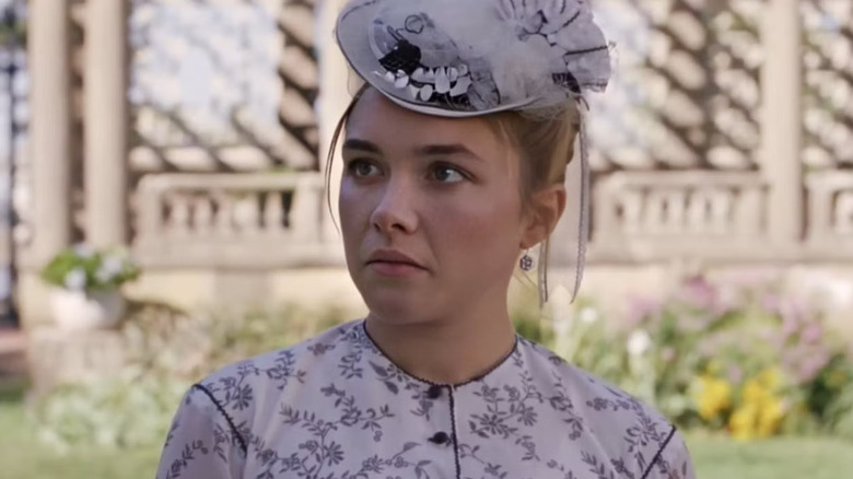 Florence Pugh as Amy March in a fancy dress and hat outside in Little Women