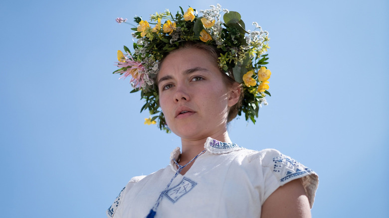 Florence Pugh as Dani wearing a May Queen crown and looking down in Midsommar