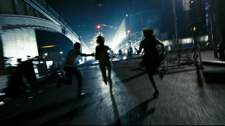 People running towards a set of traffic lights next to a bridge in New York City in Cloverfield