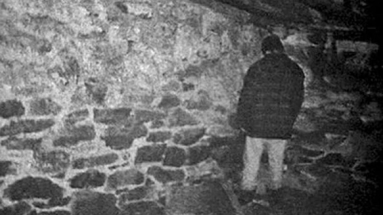 Michael C. Williams facing the corner brick wall in the basement in The Blair Witch Project