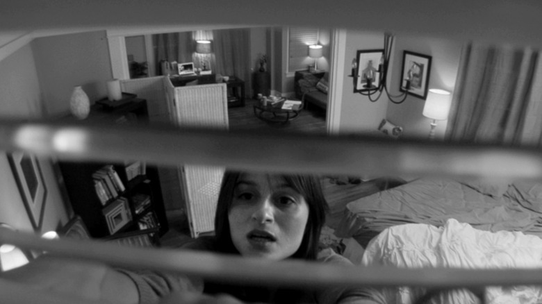 Melania Papalia as Elizabeth Benton adjusting a vent in her home with the POV of the image coming from a camera inside the vent in The Den