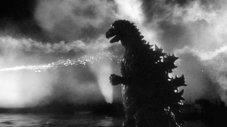 Godzilla wades through the water amid fiery explosions in Godzilla (1954)