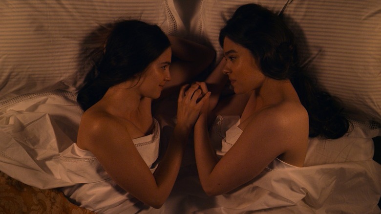 Ella Hunt and Hailee Steinfeld as Sue and Emily holding hands in bed together in Dickinson