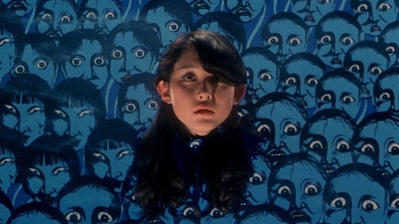 Kimiko Ikegami as Gorgeous in Hausu, with a detached head floating in front of a painted background of a bunch of wide-eyed, blue faces.