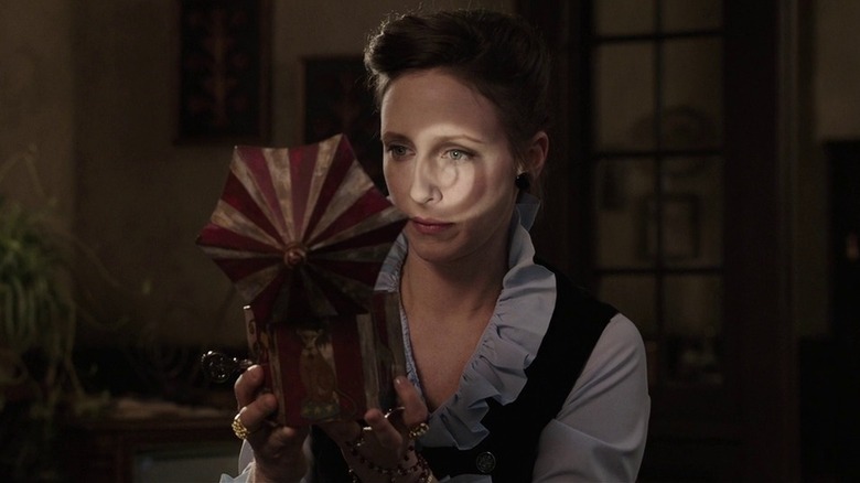 Vera Farmiga as Lorraine Warren in The Conjuring, looking at a music box with a spiral light that shines onto her face.