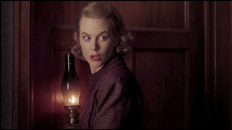 Nicole Kidman as Grace Stewart in The Others, holding a glass candle vase and talking to someone over her shoulder out of frame.