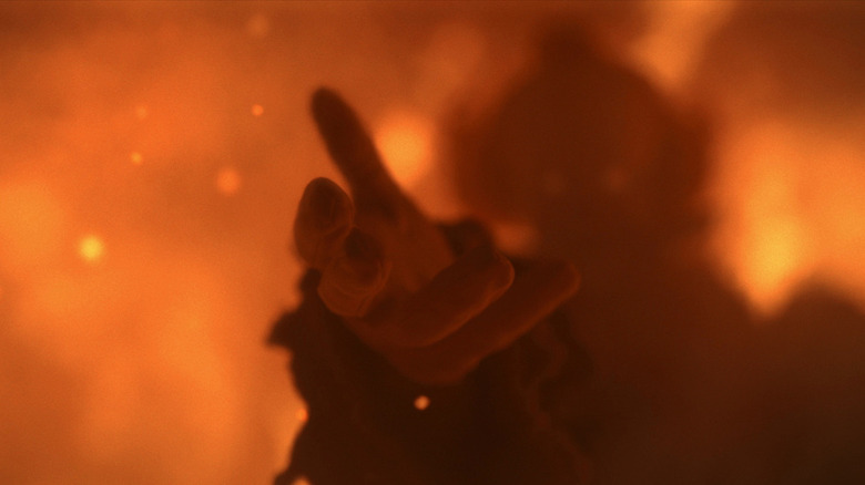 Pennywise extending his hand from the flames in "IT: Welcome to Derry"