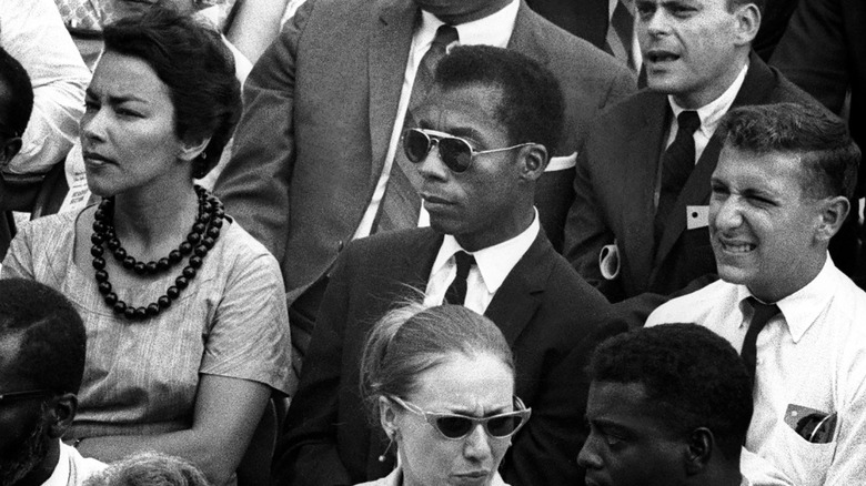 James Baldwin sits with a group of civil rights activists while wearing sunglasses in I Am Not Your Negro