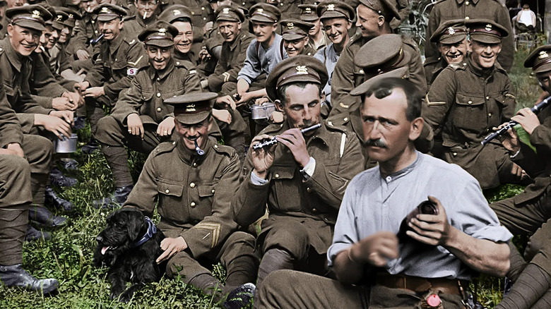 A group of World War I soldiers smile and play instruments for the camera in They Shall Not Grow Old