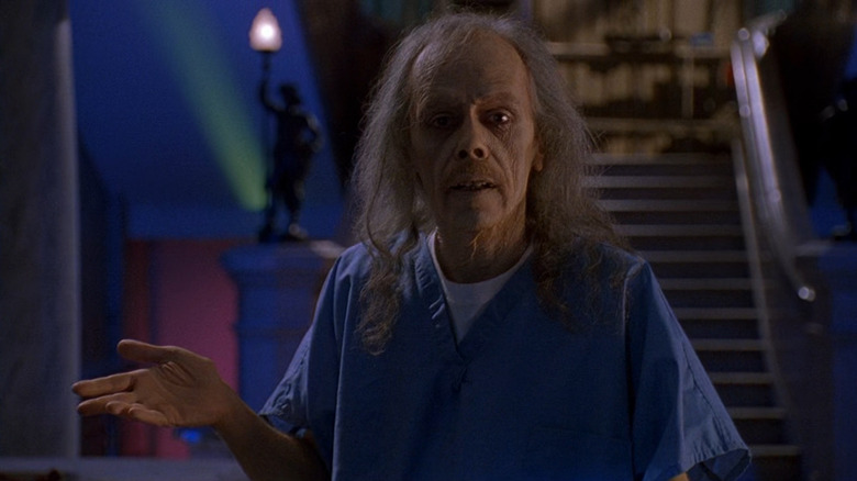 John Carpenter as The Coroner in Body Bags, wearing his blue medical scrubs as he presents to the camera in his lair.