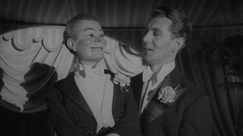 Michael Redgrave in Dead of Night performing with his puppet Maxwell, lit by the spotlight on stage.
